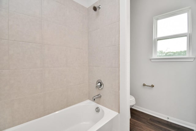 bathroom featuring tiled shower / bath combo, hardwood / wood-style flooring, and toilet