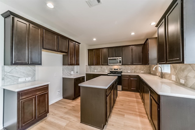 kitchen featuring appliances with stainless steel finishes, backsplash, light hardwood / wood-style flooring, and a kitchen island