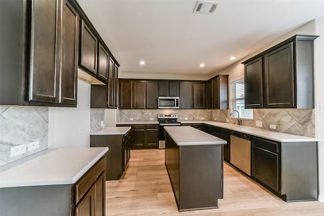 kitchen with decorative backsplash, a kitchen island, light hardwood / wood-style floors, and stainless steel appliances