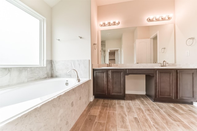 bathroom featuring hardwood / wood-style flooring, vanity, a healthy amount of sunlight, and tiled bath