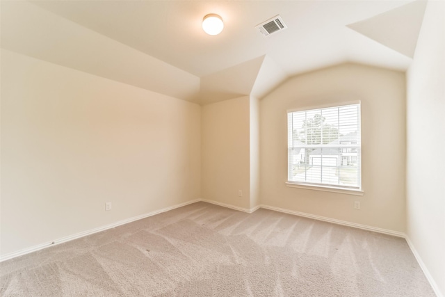 spare room with light colored carpet and lofted ceiling