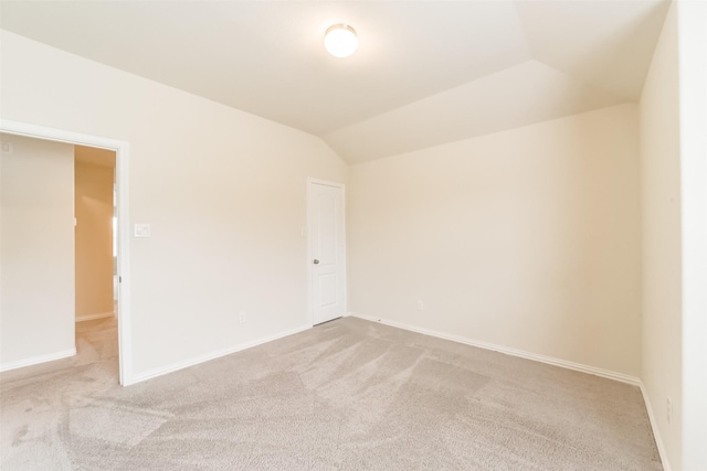 carpeted empty room with vaulted ceiling