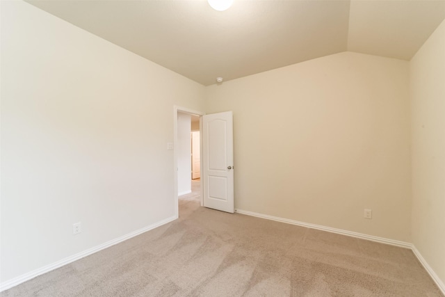 carpeted spare room featuring lofted ceiling