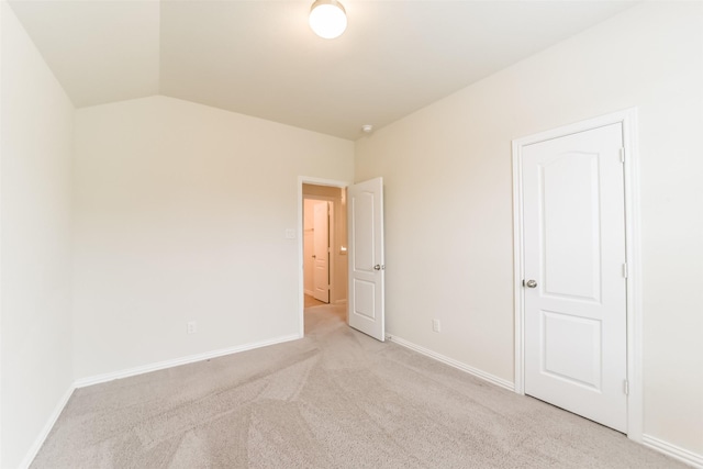 carpeted spare room with vaulted ceiling