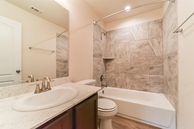 full bathroom with toilet, vanity, wood-type flooring, and tiled shower / bath