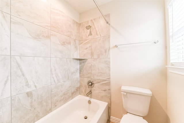 bathroom featuring tiled shower / bath combo and toilet