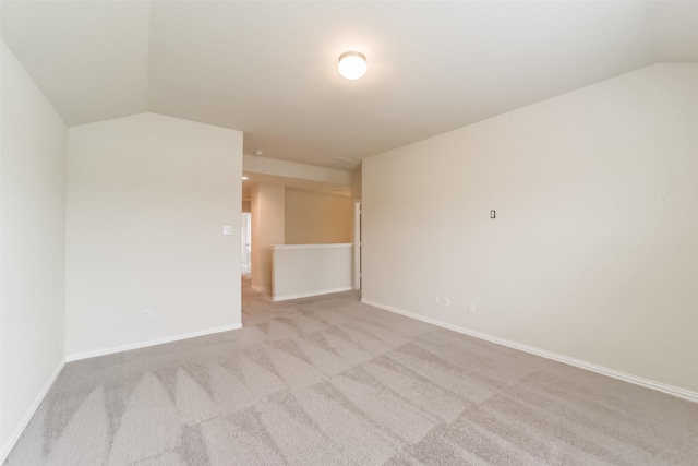 spare room featuring light colored carpet and lofted ceiling