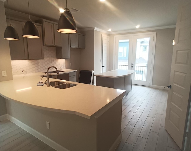 kitchen featuring sink, french doors, tasteful backsplash, kitchen peninsula, and pendant lighting