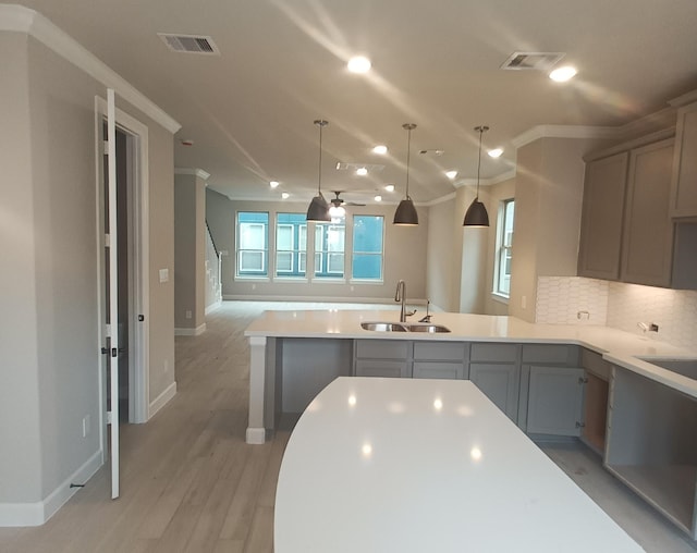 kitchen with decorative backsplash, gray cabinetry, ceiling fan, crown molding, and sink