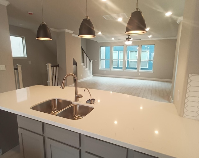 kitchen featuring light stone countertops, gray cabinetry, ceiling fan, sink, and decorative light fixtures