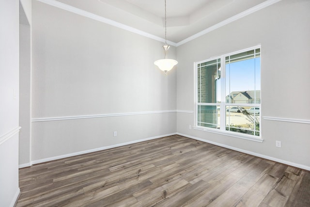 spare room with a tray ceiling, crown molding, and wood-type flooring