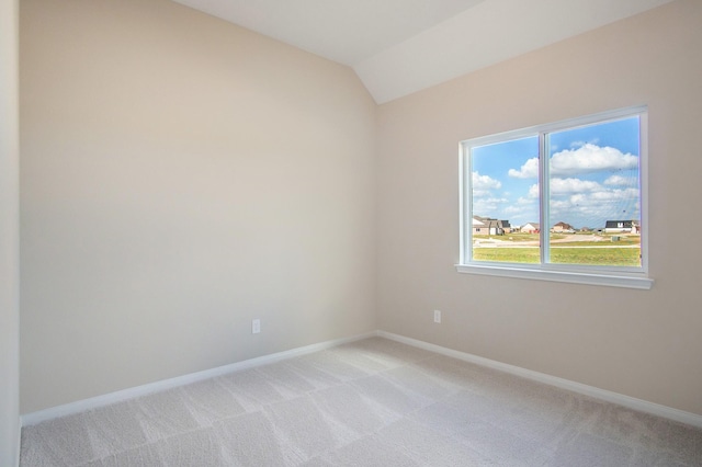 carpeted spare room featuring lofted ceiling