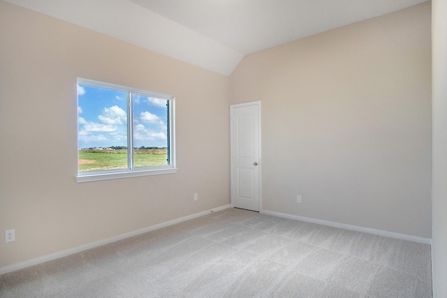 spare room with light carpet and vaulted ceiling