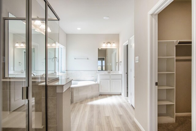 bathroom with hardwood / wood-style floors, vanity, and independent shower and bath