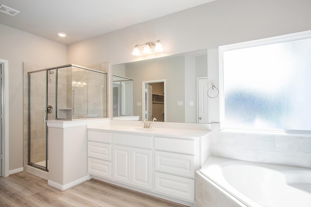 bathroom with plus walk in shower, hardwood / wood-style floors, and vanity