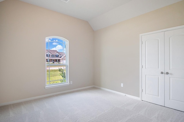 carpeted empty room featuring lofted ceiling