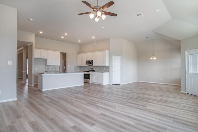 kitchen featuring tasteful backsplash, appliances with stainless steel finishes, a center island with sink, white cabinets, and light wood-type flooring