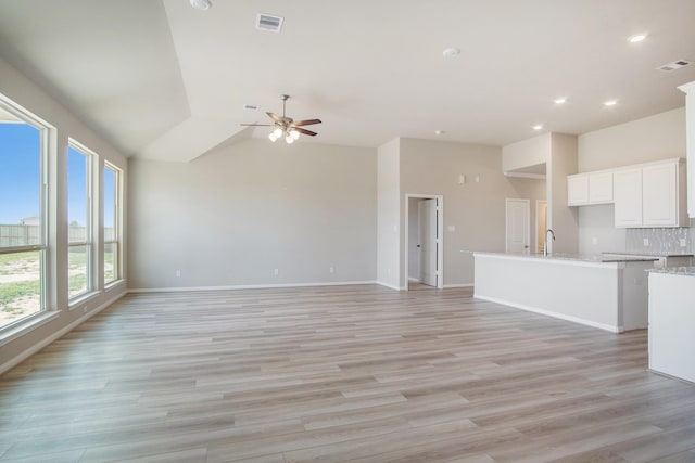 unfurnished living room featuring ceiling fan, light hardwood / wood-style flooring, and vaulted ceiling