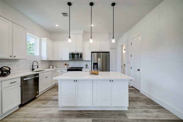 kitchen featuring stainless steel appliances, a center island, hanging light fixtures, white cabinets, and sink