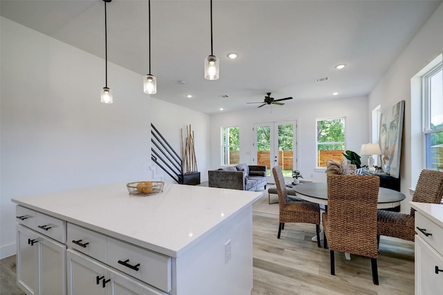 kitchen featuring ceiling fan, light hardwood / wood-style floors, white cabinets, and hanging light fixtures