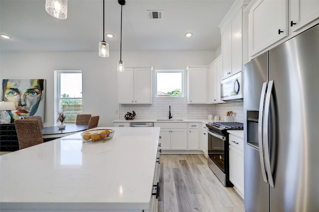 kitchen with stainless steel appliances, sink, white cabinets, and a center island