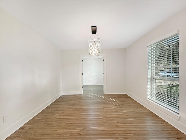 unfurnished dining area featuring wood-type flooring and a chandelier