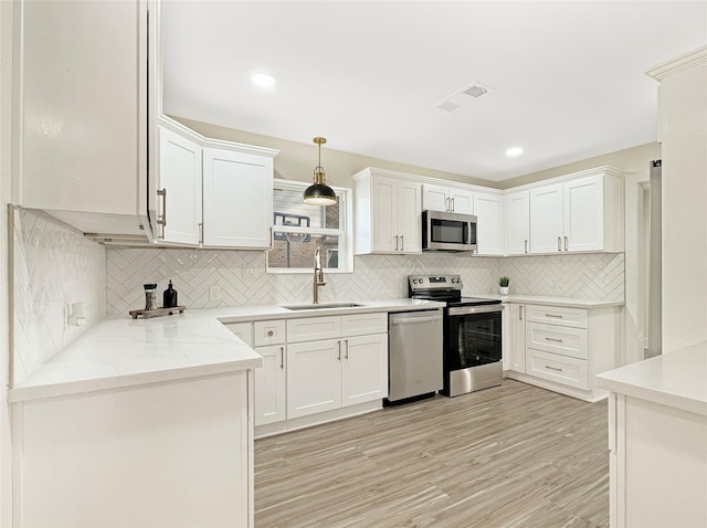 kitchen with sink, stainless steel appliances, tasteful backsplash, white cabinets, and decorative light fixtures