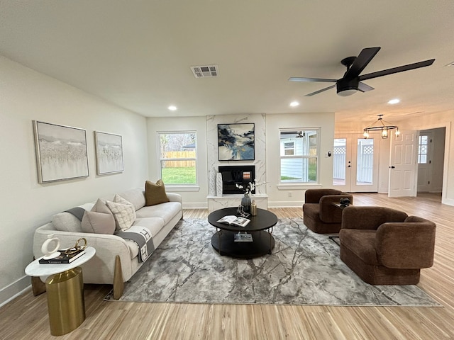 living room with ceiling fan, a high end fireplace, and hardwood / wood-style floors