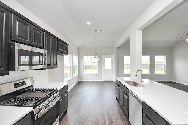 kitchen featuring sink, dark hardwood / wood-style flooring, pendant lighting, decorative backsplash, and appliances with stainless steel finishes