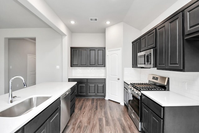 kitchen with sink, dark wood-type flooring, stainless steel appliances, and tasteful backsplash