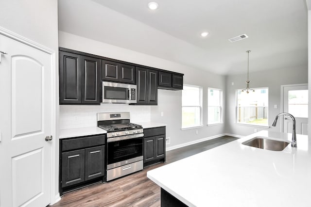 kitchen featuring hanging light fixtures, sink, dark hardwood / wood-style floors, decorative backsplash, and appliances with stainless steel finishes