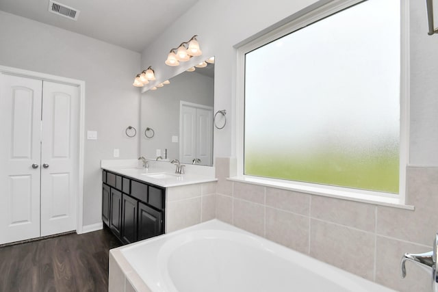 bathroom featuring vanity, wood-type flooring, and tiled tub