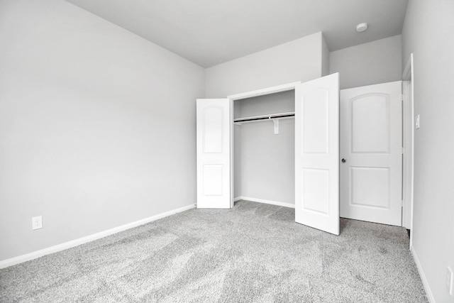 unfurnished bedroom with light colored carpet and a closet