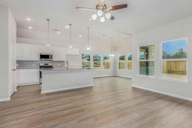 kitchen featuring a center island with sink, white cabinets, stainless steel appliances, and light hardwood / wood-style flooring