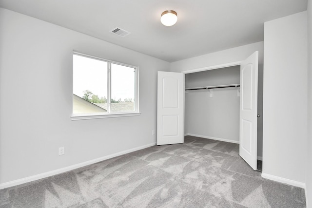 unfurnished bedroom with a closet and light colored carpet