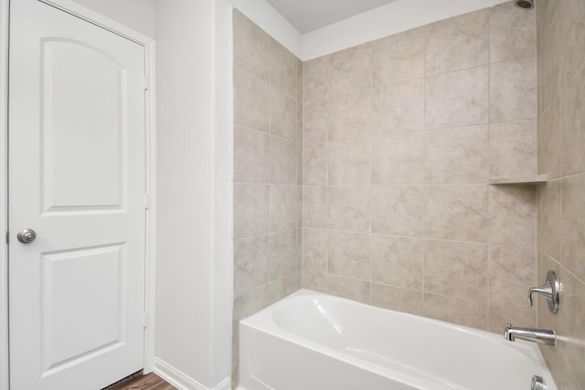 bathroom featuring wood-type flooring and tiled shower / bath