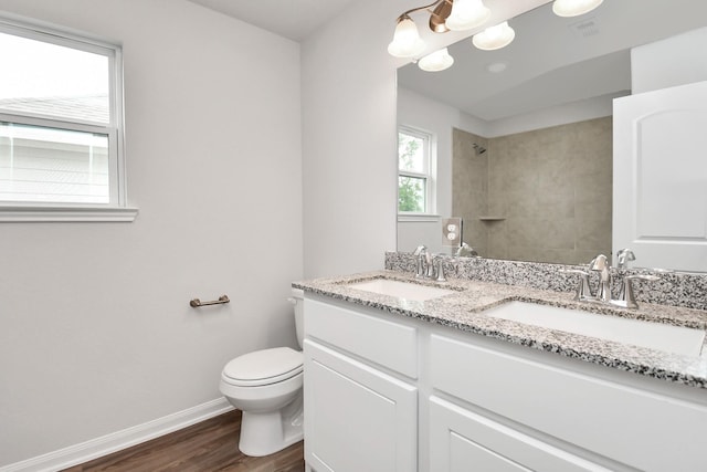 bathroom with toilet, hardwood / wood-style floors, vanity, and a tile shower