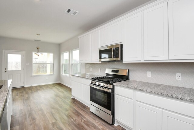 kitchen featuring hardwood / wood-style floors, stainless steel appliances, white cabinetry, and tasteful backsplash