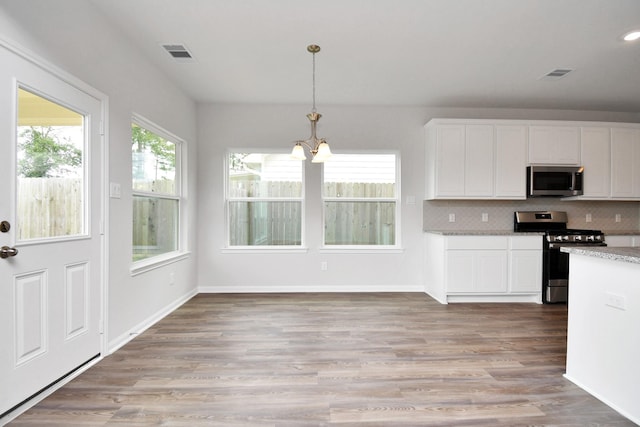 kitchen featuring light hardwood / wood-style flooring, decorative light fixtures, white cabinetry, stainless steel appliances, and a chandelier