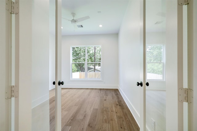 corridor with light hardwood / wood-style flooring and french doors