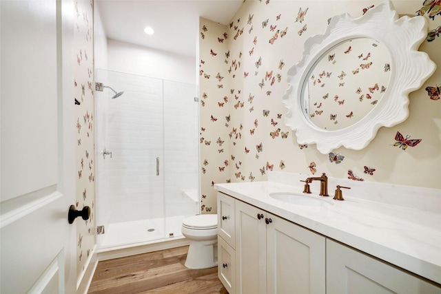 bathroom featuring vanity, wood-type flooring, a shower with shower door, and toilet