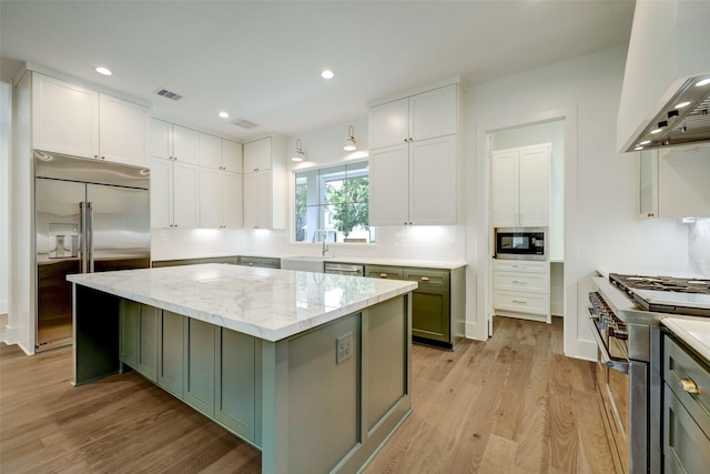 kitchen with a kitchen island, light hardwood / wood-style flooring, built in appliances, white cabinets, and green cabinetry