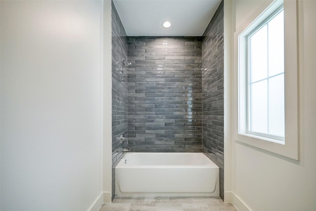 bathroom with tiled shower / bath combo and a healthy amount of sunlight