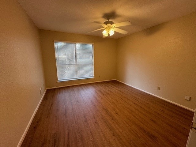 empty room featuring ceiling fan and dark hardwood / wood-style flooring