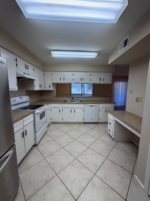 kitchen with tasteful backsplash, white appliances, sink, light tile patterned floors, and white cabinetry