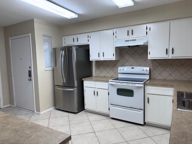 kitchen with decorative backsplash, white range with electric stovetop, white cabinetry, stainless steel refrigerator, and light tile patterned flooring