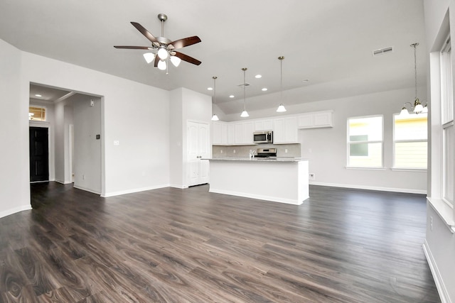 unfurnished living room with ceiling fan with notable chandelier and dark hardwood / wood-style flooring