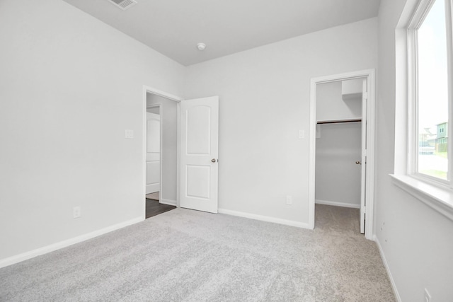 unfurnished bedroom featuring a spacious closet, a closet, and carpet