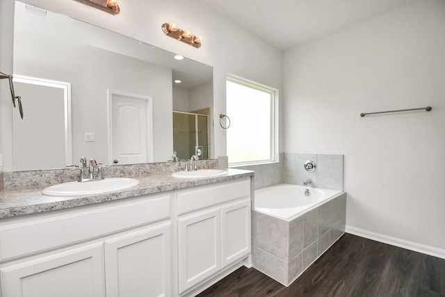 bathroom featuring vanity, wood-type flooring, and plus walk in shower