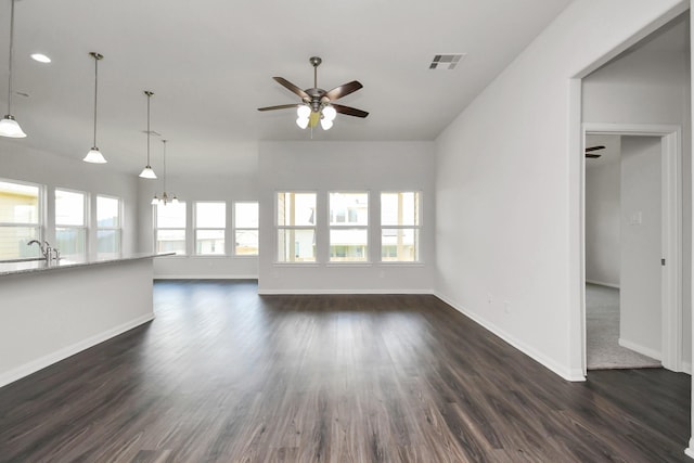 unfurnished living room featuring ceiling fan with notable chandelier, dark hardwood / wood-style flooring, and sink